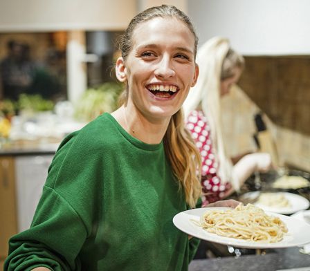 Young female carer serving up a spaghetti dinner  